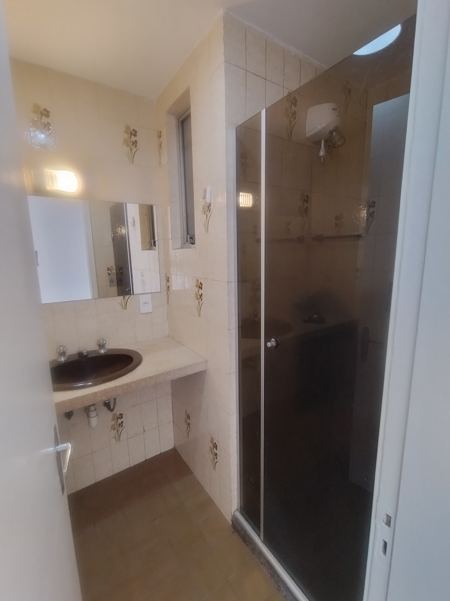 Banheiro com box em vidro, bancada em granilite e espelho