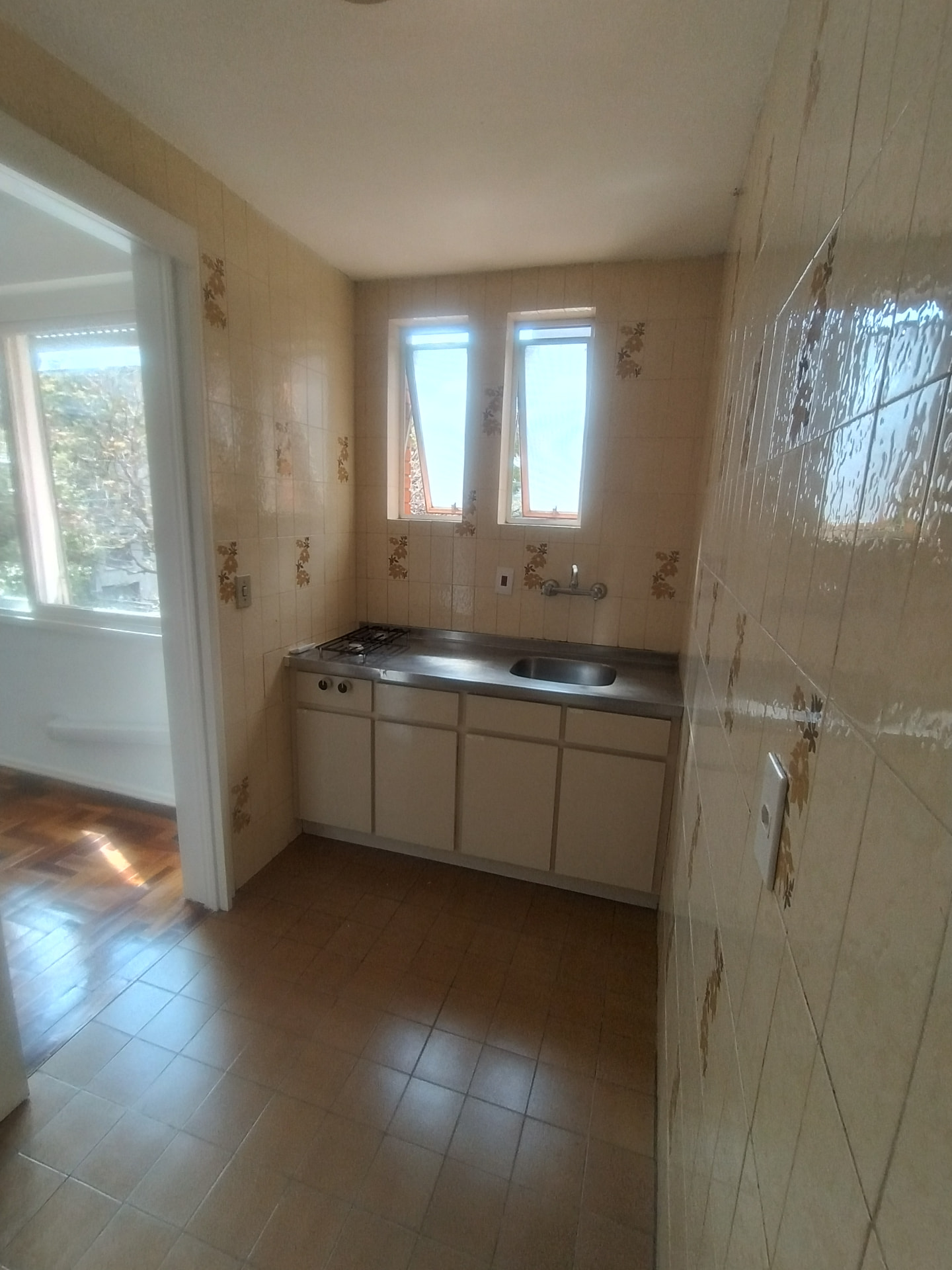 Cozinha com bancada em inox, armários brancos e azulejos decorados