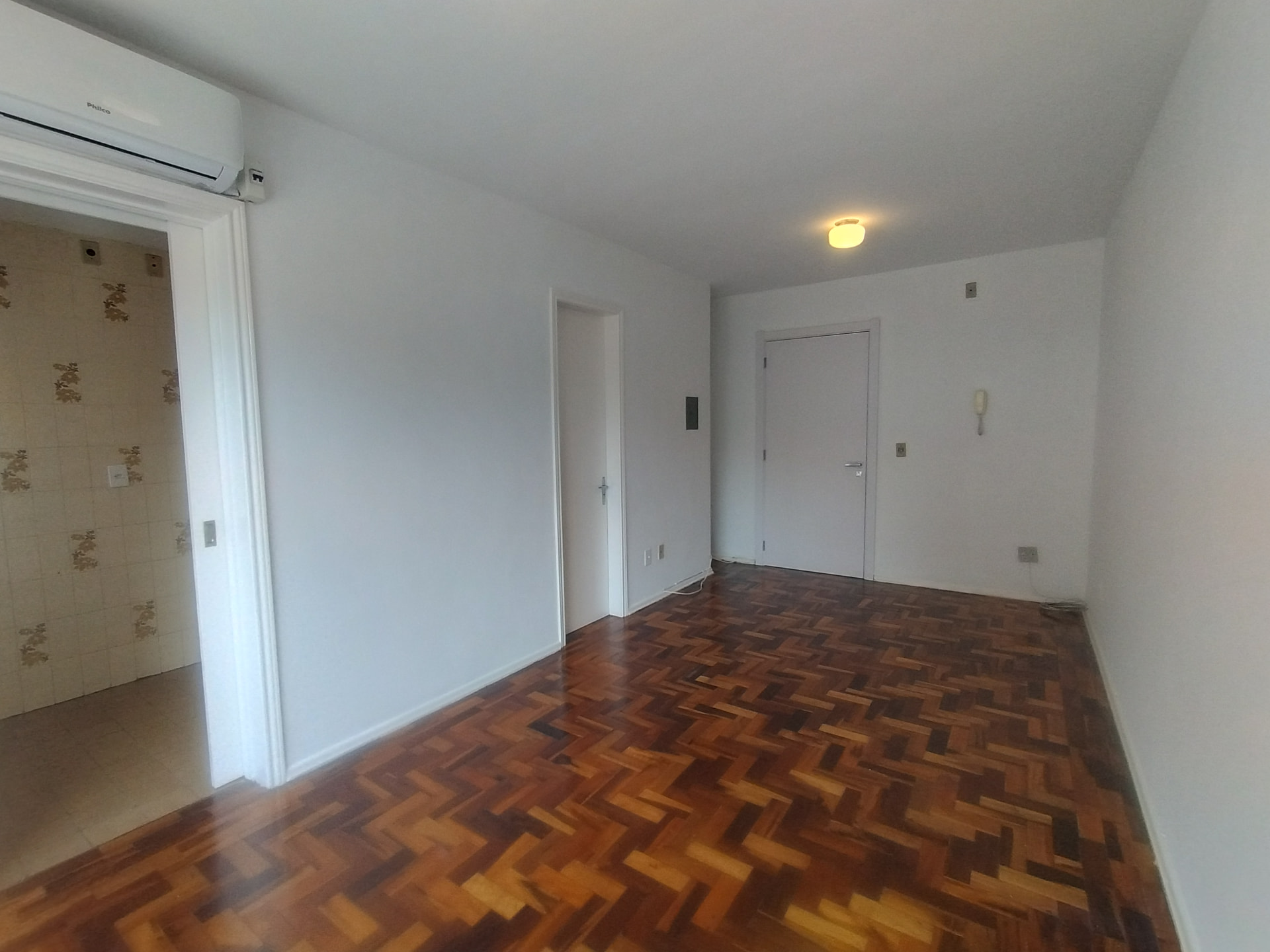 Segundo ângulo da sala com porta de acesso à cozinha e interfone