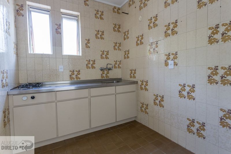 Cozinha com bancada em inox, armários brancos e azulejos decorados
