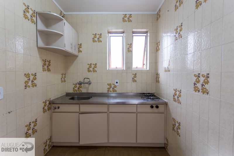 Cozinha com bancada em inox, armários e revestimentos cerâmicos