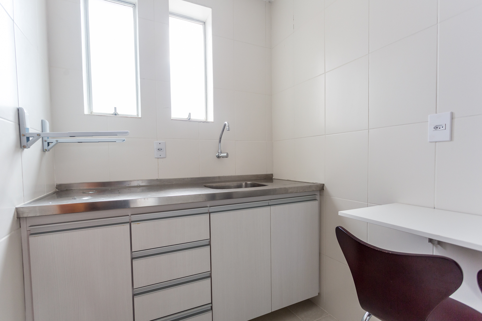 Cozinha com bancada de inox e armários brancos